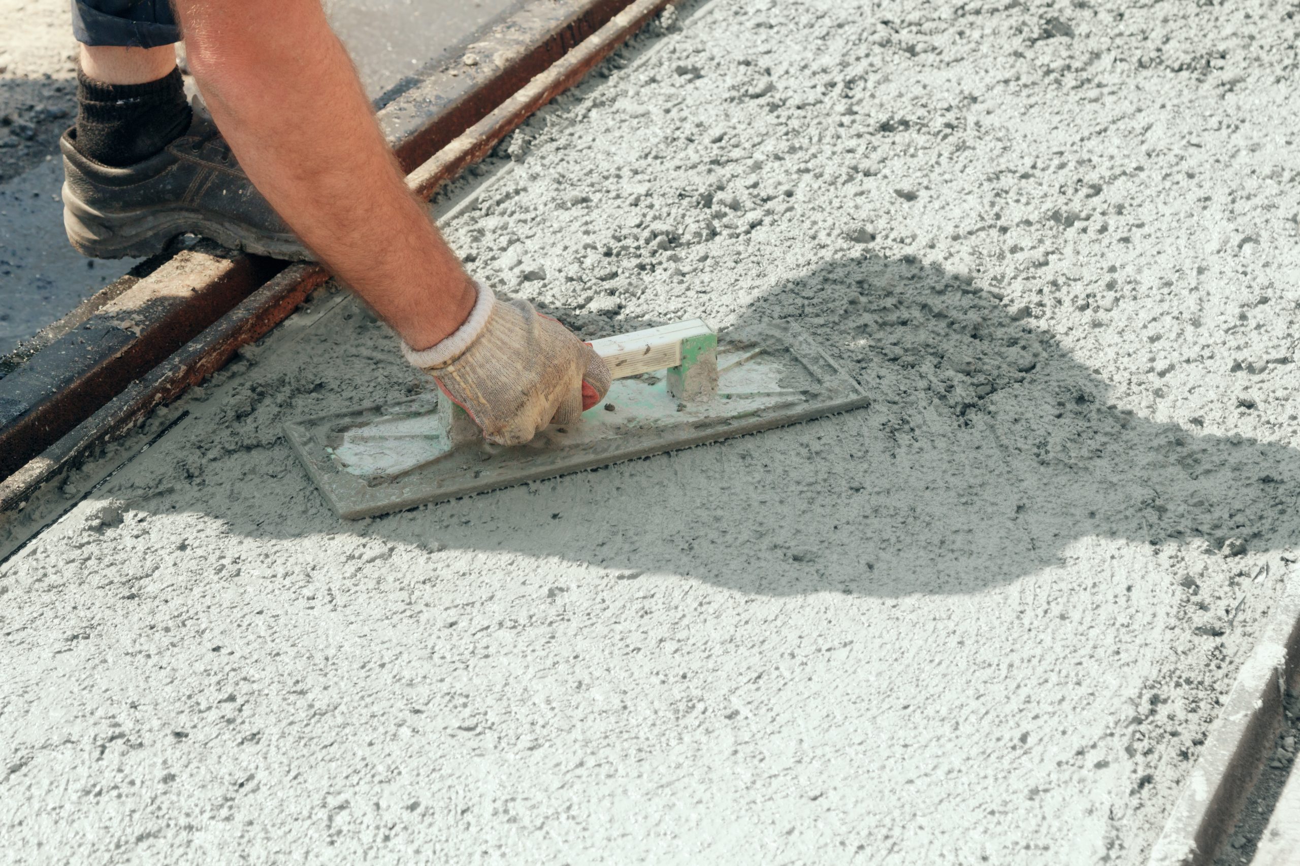 Construction worker leveling concrete pavement.